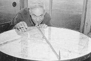 Hiram Denton, then the observer on Whiteface, demonstrates the use of an alidade, an instrument for determining the location of forest fires.