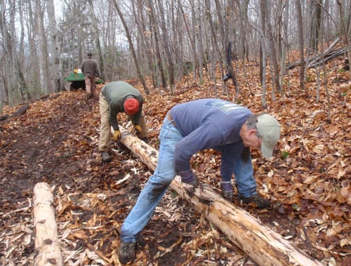 shaving bark Tim Holmes, front, and Jim Sausville shave bark from a log used in the construction of a bridge at Dewey Mountain Ski Center. Photo by Phil Brown.