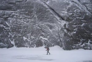 A skier crosses Avalanche Lake near the cliffs of Mount Colden.