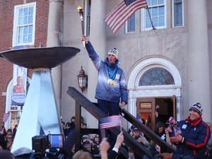 Olympic skier Billy Demong raises a victory torch after a parade in Saranac Lake. Photo by Phil Brown.