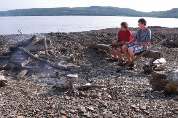 Aspiring gourmets Peter Curtis and Nicholas Mann roast hot dogs over a campfire.