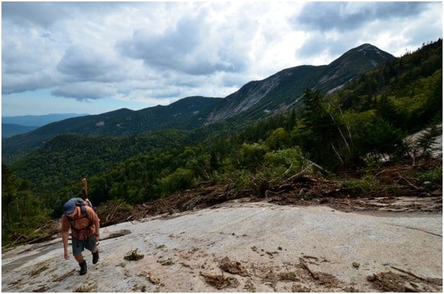 slide hiker A hiker climbs a new slide on Saddleback Mountain the day after Hurricane Irene. Photo by Brendan Wiltse.