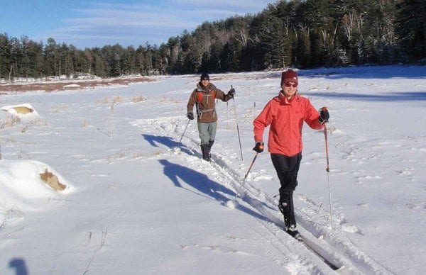 Kim Martineau and Ethan Rouen cross a snowy East Mill Flow. Photo by Phil Brown.