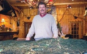 Tom Lawson stands behind a model of the Adirondack Club and Resort. Photo by Mike Lynch