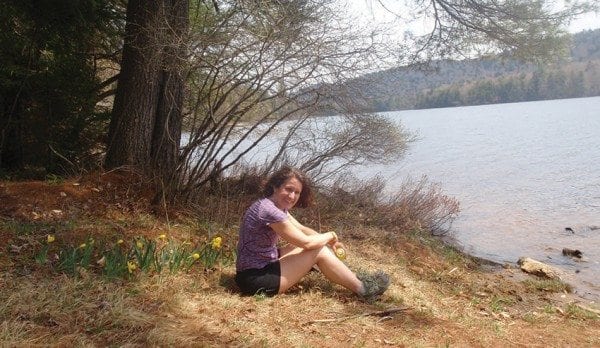 Carol Fox relaxes beside the flowers and pines on the shore of Cascade Lake in the Pigeon Lake Wilderness. Photo by Phil Brown