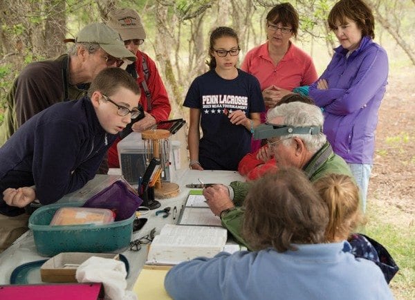 Birders gather at the Crown Point Birding Station in May as station coordinator Gordon Howard bands a warbler. Photo by Mike Lynch