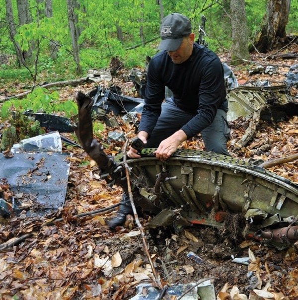 Scott Van Laer grapples with a piece of a Navy plane that crashed in 1945. Photo by Kenneth Aaron