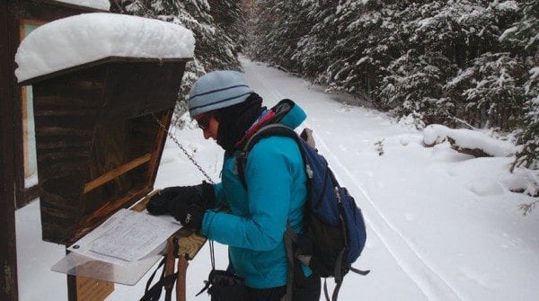 Carol signs in before heading off on a ski trip to Glasby Pond. Photo by Phil Brown