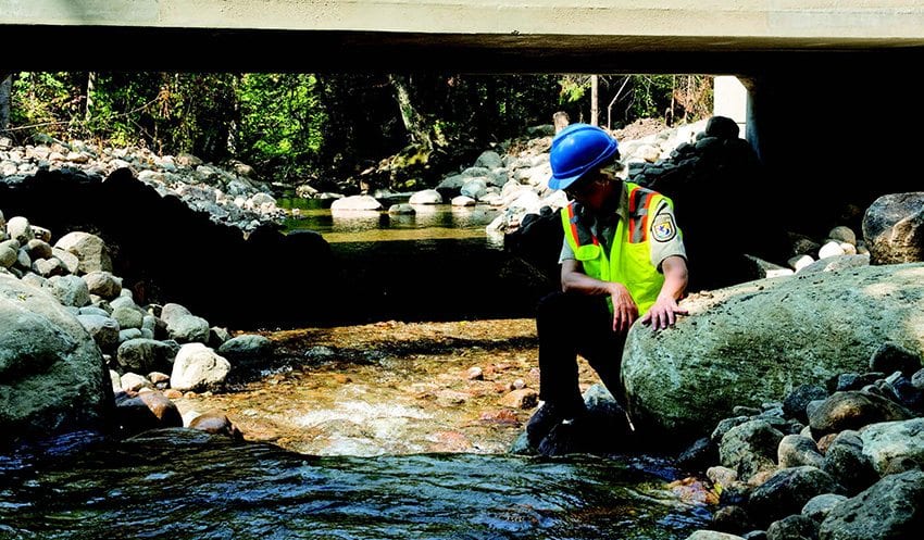 U.S. Fish and Wildlife Service biologist Madeline Little surveys the water on Roaring Brook in Lake Placid near a bridge built to withstand flooding and facilitate fish passage. Photo by Mike Lynch