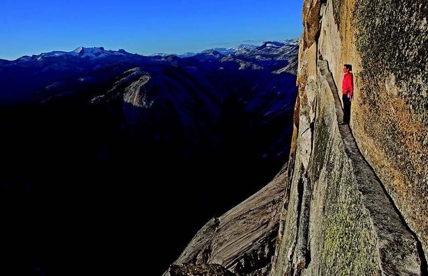 Alex Honnold hangs out on the Thank God Ledge while climbing, without a rope, the North Face of Half Dome in Yosemite National Park. He is about 1,800 feet off the ground. Photo by Jimmy Chin