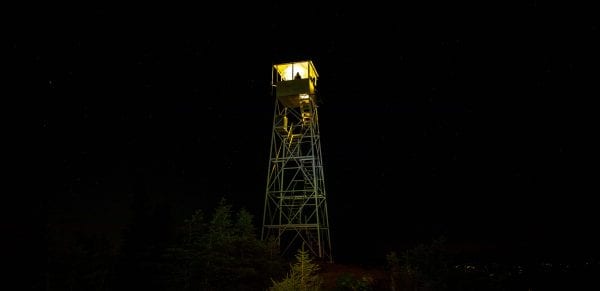 The Hurricane Mountain fire tower cab was lit by a lantern Saturday, August 31. The lighting was a statewide event to raise awareness of fire towers.  Photo by Mike Lynch