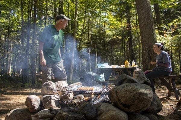 Adirondack 46er Trail Master Sam Eddy talks to Adirondack Explorer Publisher Tracy Ormsbee as he cooks hot dogs at the Sand Lake lean-to in the Five Ponds Wilderness. Photo by Mike Lynch