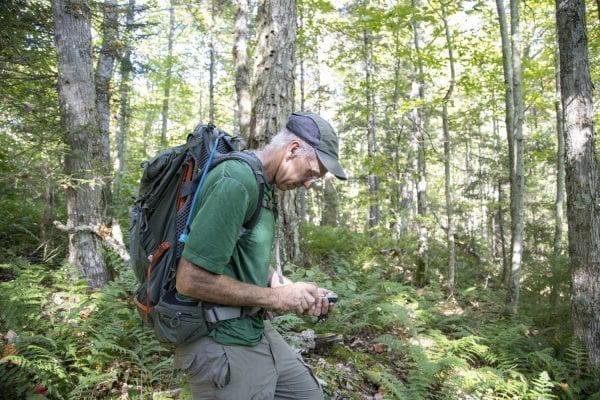Sam Eddy looks at his GPS in the Five Ponds Wilderness. Photo by Mike Lynch