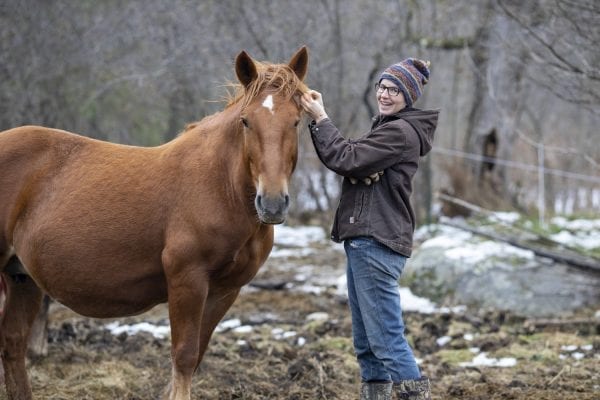 small farm owner standing with a horse