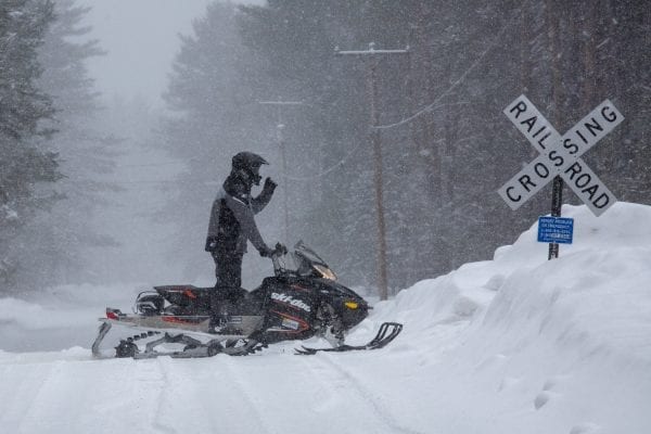 A snowmobiler stops on the much debated railroad line in Lake Clear in February 2019. Advocates of a rail trail have said the corridor would make a great biking and snowmobile trail with the tracks gone. Photo by Mike Lynch