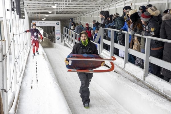 A track worker carries a sled off the track during a luge competition at Mount Van Hoevenberg in late February. Photo by Mike Lynch