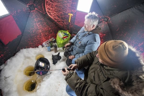 Guide Matt Burnett, left, and Explorer writer Tim Rowland fish in an ice shanty. Photo by Mike Lynch