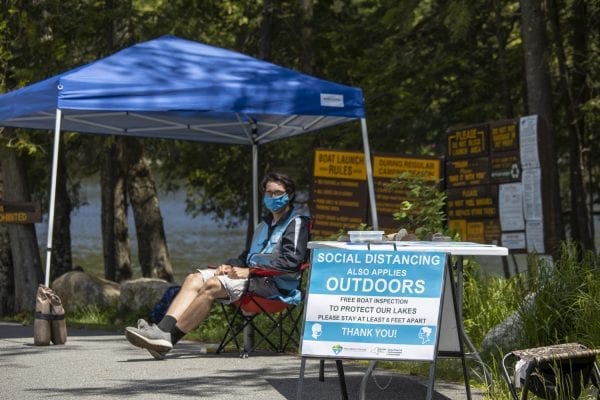 An Adirondack Watershed Institute boat steward waits for action at the Second Pond boat launch outside of Saranac Lake in June. Although this steward was enjoying a break, waters were busy with boaters this year. Photo by Mike Lynch