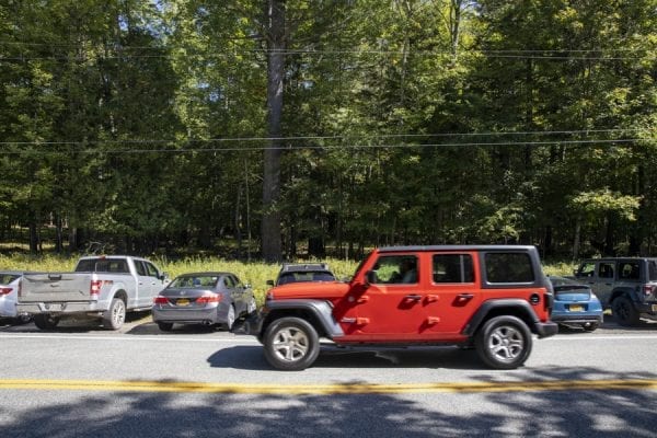 A jeep drives past vehicles that are parked illegally along Route 73 next to the Giant Mountain trailhead in St. Huberts. The vehicles are also parked perpendicular to the road. Photo by Mike Lynch