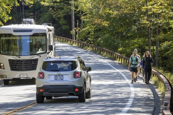 Hikers walk along Route 73 causing a vehicle to swerve away from them. Parking was an issue throughout the summer for hikers due to the high volume of people coming to the Adirondacks. Photo by Mike LYnch