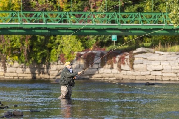 Rich Redman fishes near a walkway over the Saranac River. Photo by Mike Lynch