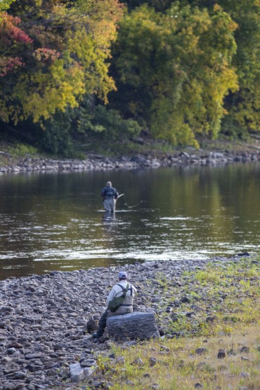 Herb Colby watches his friends fish for a few minutes on the Saranac River. Photo by Mike Lynch
