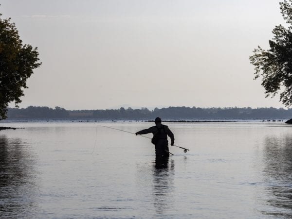 An angler adjusts his gear at the mouth of the Saranac River. Photo by Mike Lynch