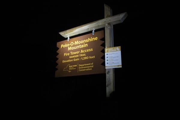 The Poke-O-Moonshine Ranger trail sign lit up by a headlamp. Photo by Mike Lynch