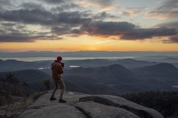 Shane Kenyon walks on the summit of Poke-O-Moonshine Mountain in the eastern Adirondacks at sunrise. photo by Mike Lynch