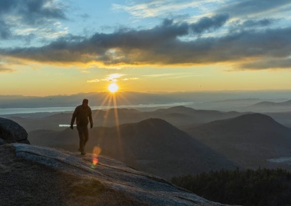 Shane Kenyon walks on the summit of Poke-O-Moonshine Mountain in the eastern Adirondacks at sunrise. photo by Mike Lynch