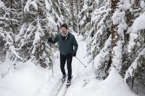 Bob Erickson, a Piseco resident and trail volunteer, makes his way through the snow-covered evergreens. Photo by Mike Lynch