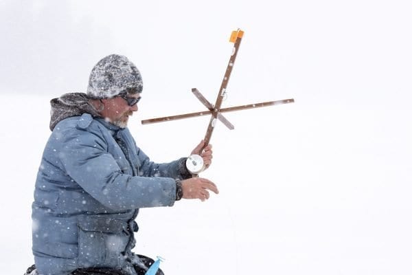 Guide Matt Burnett checks the line of one of the tip ups on Osgood Pond. Photo by Mike Lynch