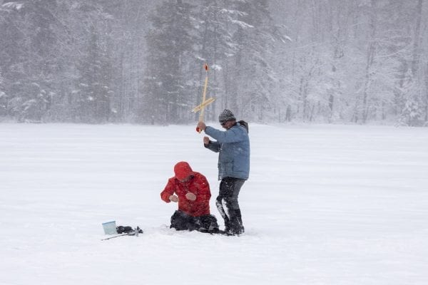 Glenn Goldman, left, checks the line for fish on Osgood Pond on a frigid February day as guide Matt Burnett assists him. Photo by Mike Lynch