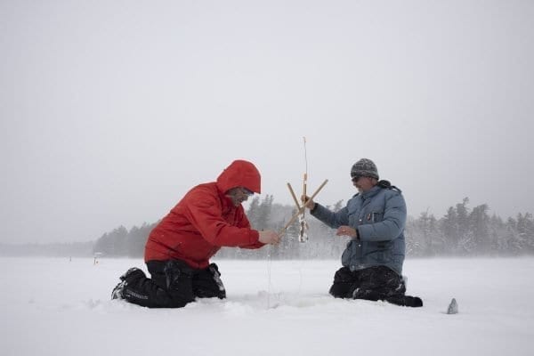 Glenn Goldman, left, pulls a northern pike from Osgood Pond on a frigid February day as guide Matt Burnett looks on. Photo by Mike Lynch