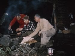 Clarence Petty helps a legislative fact-finding team make dinner over a campfire in 1961.