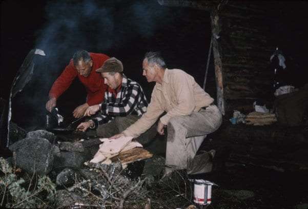 Clarence Petty helps a legislative fact-finding team make dinner over a campfire in 1961.