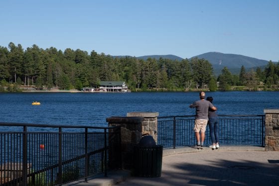 A couple looks across Lake Mirror to the Adirondack Mountains from Lake Placid's waterfront.