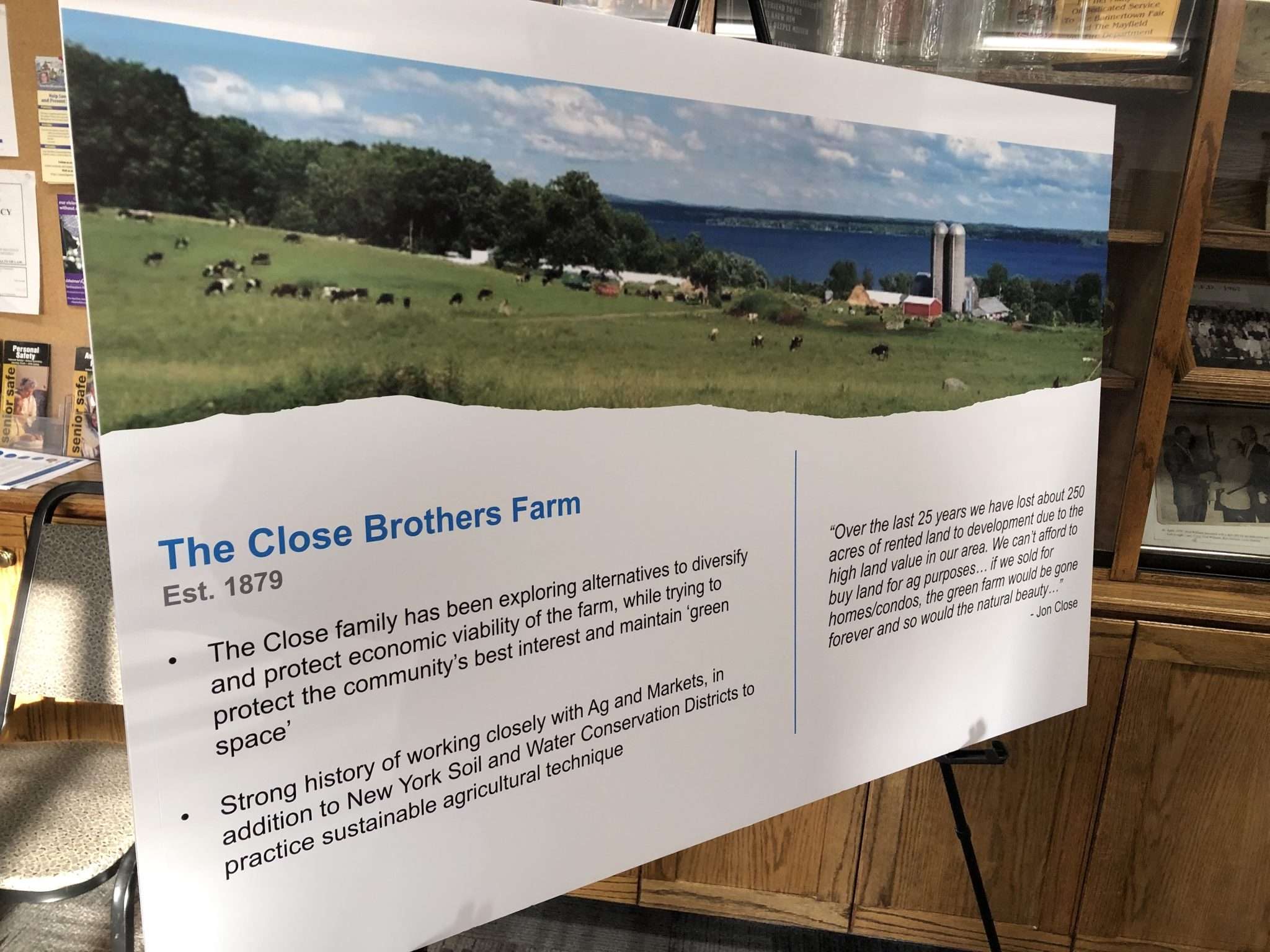 A poster board shows a photo of the Close Brothers Farm in Mayfield with a view of Great Sacandaga Lake in the distance.