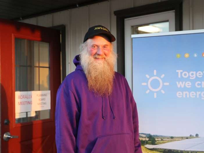Jon Close, a farmer from Mayfield with a long beard and wearing a purple sweatshirt, stands outside the Mayfield Fire House.