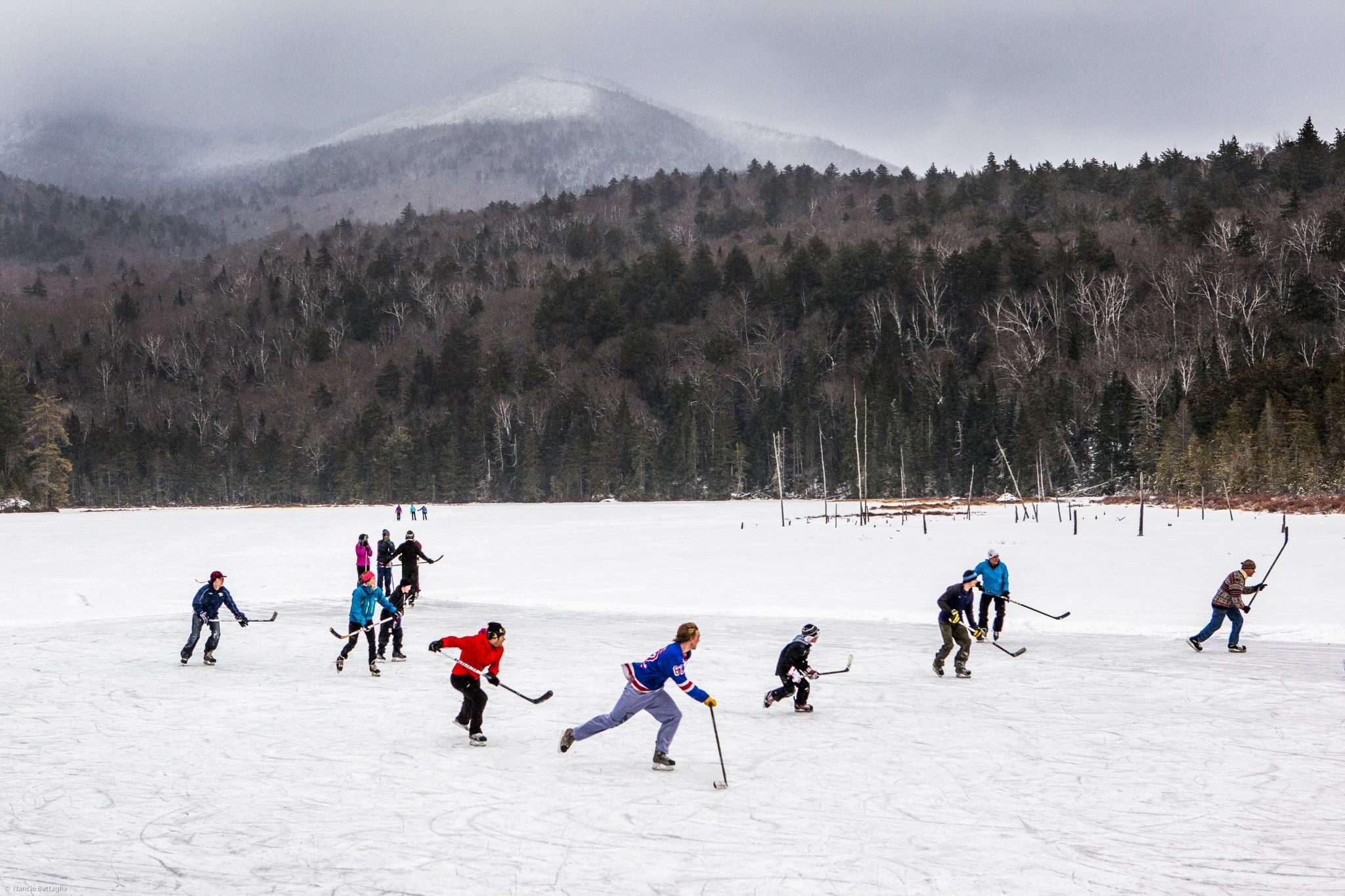 A group of 12 skaters play over frozen Holcomb Pond near Lake Placid, New York.
