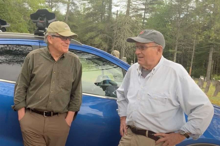 Dan Forbush (left, wearing a green shirt) and Bill Walker in a white shirt, stand next to a blue car. Their Cliff-Redfield Initiative is working on an oral history project for Warren County