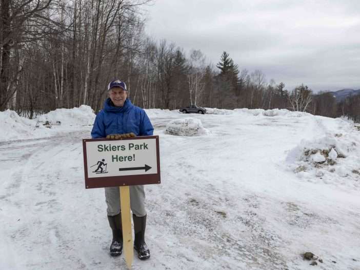 Ed Palen stands in front of a parking lot on his property that he created in recent years to accomodate skers visiting the Keene section of the Jackrabbit Trail. Photo by Mike Lynch