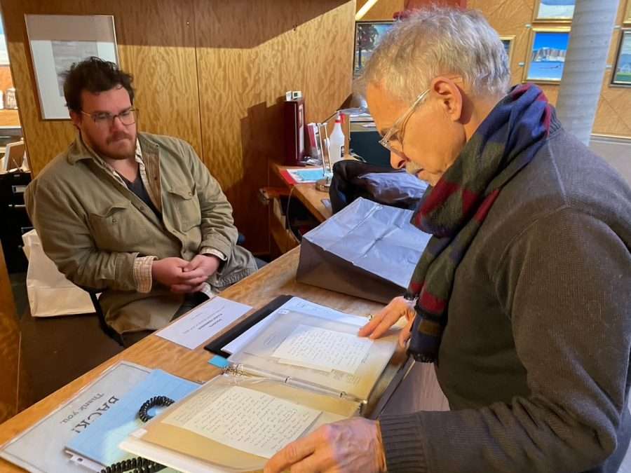 Walter Early, museum preparator for the Plattsburgh State Art Museum,in a green shirt, and Rockwell Kent scholar Scott Ferris, wearing a black shirt and scarf, examine documents from the Kent collection.