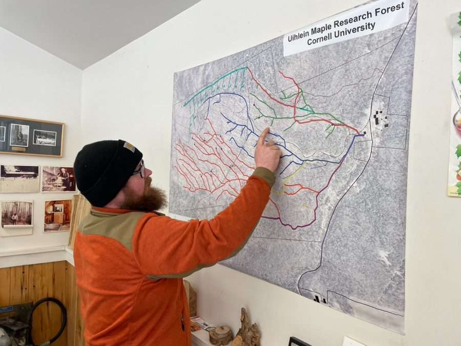 Keith Otto in an orange shirt points to a map of the Maple Trail and hundreds of miles of tubing.
