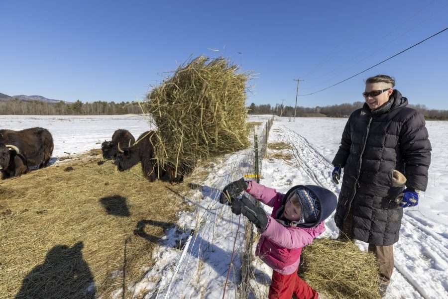 girl at a farm fence with woman in long black coat