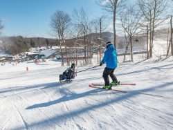 Ski instructor is tethered to the skier's bi-ski on a Gore Mountain slope.