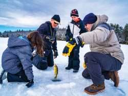 people surrounding a hole in the ice and pulling out a fish