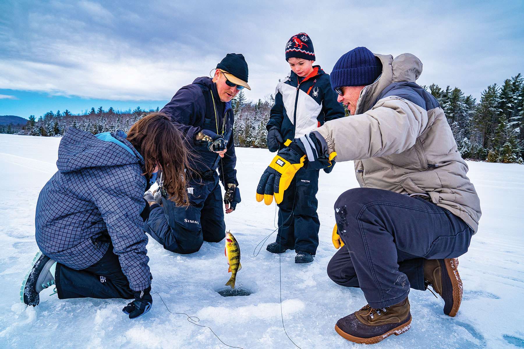 ice fishing: people surrounding a hole in the ice and pulling out a fish