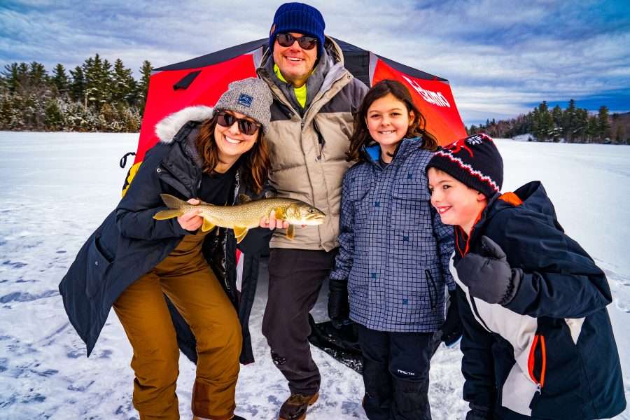 family poses for photo with fish they caught while ice fishing