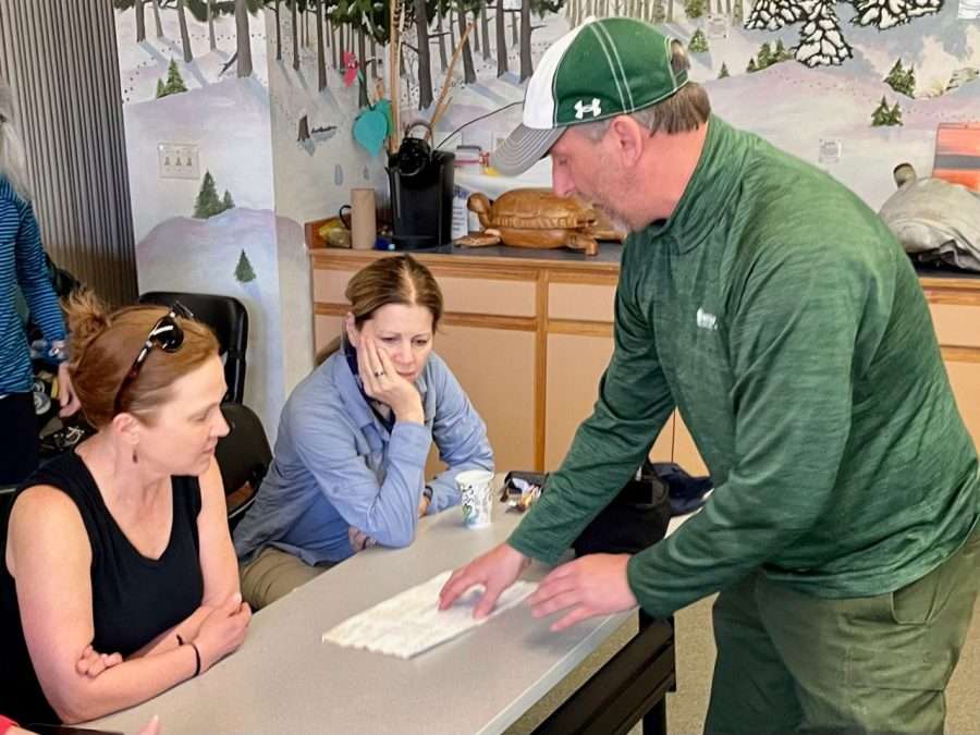 Scott van Laer, director of Paul Smith’s VIC, wearing green, shows a document to Ellen Miller (left) and Sherri York.
